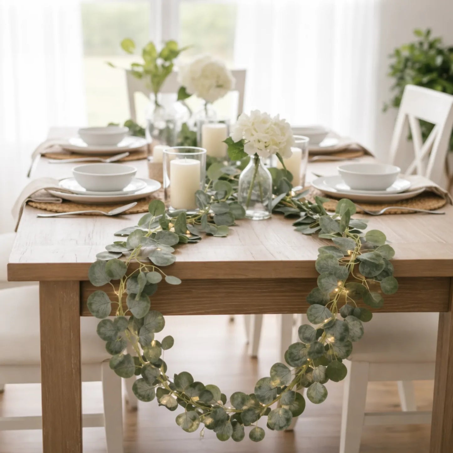 Dining table set with greenery and candles in a bright room