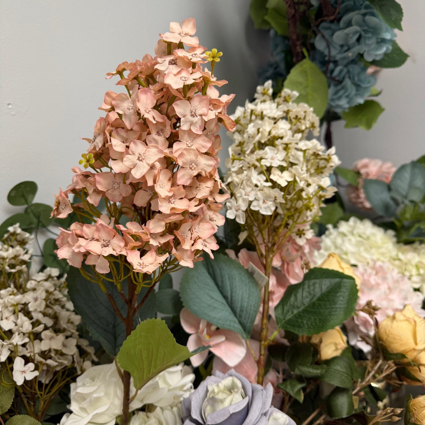 Close-up of a bouquet of artificial flowers with pink, white, and green colors.