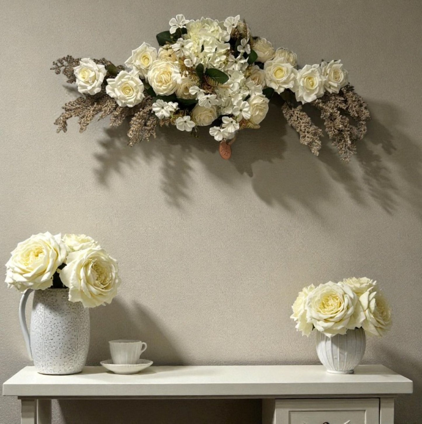 Floral arrangement on a wall above a table with flowers in vases.